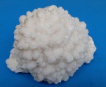 A geological sample formed of bright snow coloured clusters of tiny crystals,