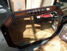 A carved oak mirror with bevelled glass,
