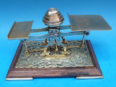 A set of brass and oak postage scales with weights to centre