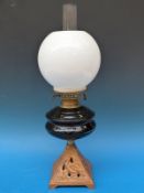 A cranberry glass oil lamp with shade on cast iron base in the form of an ibis