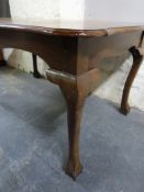 A shaped walnut dining table raised on ball and claw cabriole legs (W150, W98,