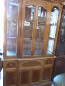 A glass framed display cabinet with single door to base and carved decoration to top