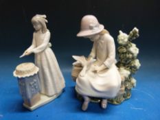 Two Nao figures comprising girl cutting a cake and girl on a bench with doves