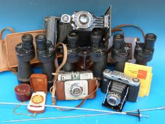 A collection of vintage binoculars and cameras including Zeiss Ikonta,