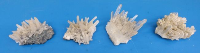 A group of four small geological samples in the form of long angular crystals,