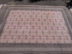 A large wool rug with multiple geometric borders with four rows of 10 guls on a pink ground (315cm