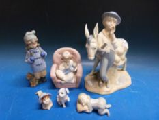 A Nao figure of a girl nursing a doll together with a Spanish model of a boy with donkey and other