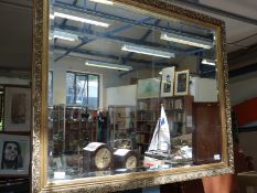 A large gilt stucco framed mirror in bevelled glass,