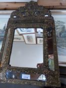 A 19thC/20thC brass cushion mirror with scrolling decoration and lion pediment
