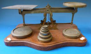 A set of brass postage scales on a oak base with a run of weights ½ oz to 3lb