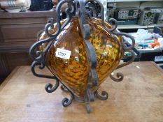 A cast iron framed amber glass hanging lamp, the glass with dimpled decoration and bulbous in form,