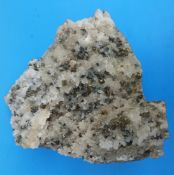 A geological sample of small white crystals with scattered iridescent stone and fools gold,