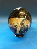 An ostrich egg painted with two leopards sitting on tree branches and signed Julie Morgan