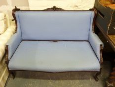 An upholstered mahogany framed sofa with scrolling carved detail.