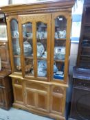 A glass framed display cabinet with single door to base and carved decoration to top (W116 x D42 x