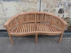 A teak banana-shaped garden bench