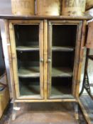 An oriental bamboo and lacquer display cabinet with three shelves behind double doors (H100 x
