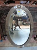 An Arts and Crafts style copper oval mirror with hammered finish,