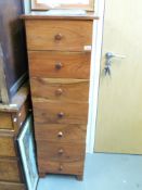 A narrow fruitwood chest of seven graduated drawers (W43 x D37 x L131cm)