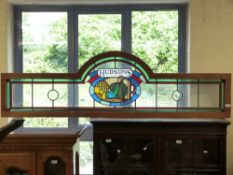 A Hudsons stained glass panel with central panel depicting a gentleman with monocle lifting a dome