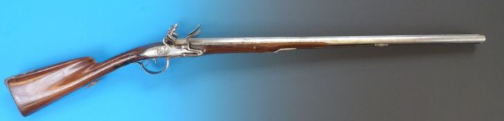 A 20 bore double barrelled flintlock gun with carved walnut stock,