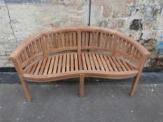 A teak banana-shaped garden bench