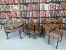 A rest of tables with carved oriental design together with a circular table of similar design