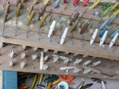 Over 100 fishing minnows in various stages of construction, some complete and painted on stands.