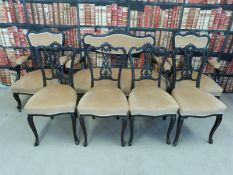 An ebonised salon suite consisting of a sofa and six chairs (2 carvers) upholstered and with carved