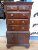 A reproduction miniature chest-on-chest with brass ring handles and bracket feet (W38 x D28 x