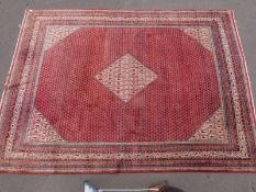 A large Iranian rug with all over geometric design on red ground (385 x 280cm)