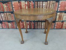 An oval walnut table raised on cabriole legs with ball and claw feet,