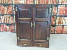 An antique oak wall cabinet with panelled doors and two drawers below (W69 x D31 x H90cm)
