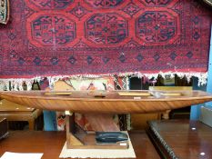 A large teak model yacht hull on stand