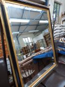 A large bevelled gilt and ebonised framed mirror (110cm x 40cm overall)