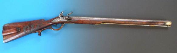 A Continental 20 bore flintlock rifle with ornately carved stock and trigger guard, brass mounts,