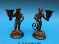 A pair of bronze chamber sticks in the form of monkeys holding sconces