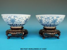 A pair of Chinese blue and white bowls on carved wooden stands (12cm diameter)