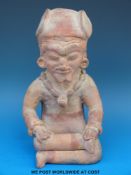 A Mayan terracotta figure in the form of a seated man wearing a necklace, 23cm tall.