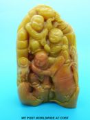 An unusual carved yellow soapstone boulder with three figures holding fruit and other items (15cm