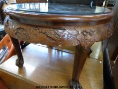 A Chinese carved dark elm glass topped round coffee table with four quarter smaller tables under.