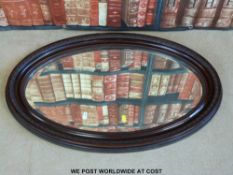 An oval carved mirror with bevelled glass (max diameter 81cm)