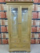 A modern solid oak display cabinet with beveled glass to the sides and two front doors,