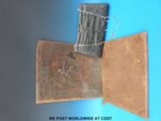 A leather embossed folder depicting a lady at a loom with a spinning wheel,