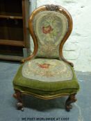 A Victorian walnut carved spoon back button upholstered nursing chair with scroll turned ends,