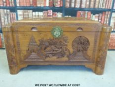 A Chinese camphor wood carved elm lined chest featuring a fisherman,
