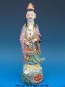 A 19thC Chinese famille rose figure of a courtesan standing on a rock with stylised face and