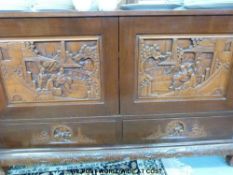 A Chinese elm desk sideboard the cupboard panels carved with three people by a bridge and houses