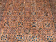 A large wool rug with navy coloured geometric and floral design on a deep cherry red ground (253cm