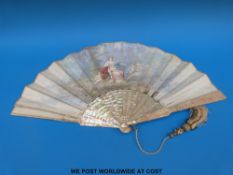 A hand painted mother-of-pearl fan with decoration of a  woman in loose garments relaxing outside